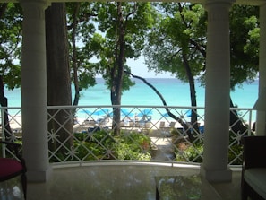 Balcony view of Iskele Long Beach with sun loungers and palm trees under a clear blue sky.