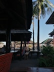 Outdoor seating area beside the Ek Tem Villa’s pool, shaded by tall tropical trees.