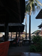 Outdoor seating area beside the Ek Tem Villa’s pool, shaded by tall tropical trees.