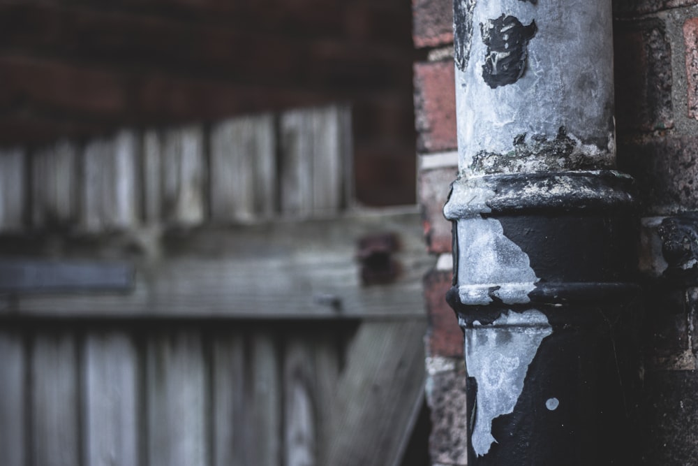 a close up of a metal pole near a brick wall