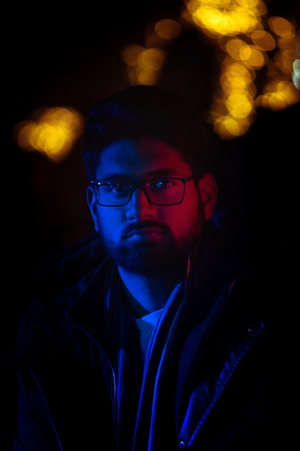 a man with glasses and a beard in the dark