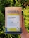 A package of Doma Coffee Roasting Company's Colombia organic huila coffee is held in someone's hand. The packaging highlights flavors of vanilla, grape, and cashew, with a medium roast level indicated. The text mentions the coffee's origin from the Aipe, Huila region of Colombia, and emphasizes its sweet flavors and syrupy body. The background features vibrant green foliage.