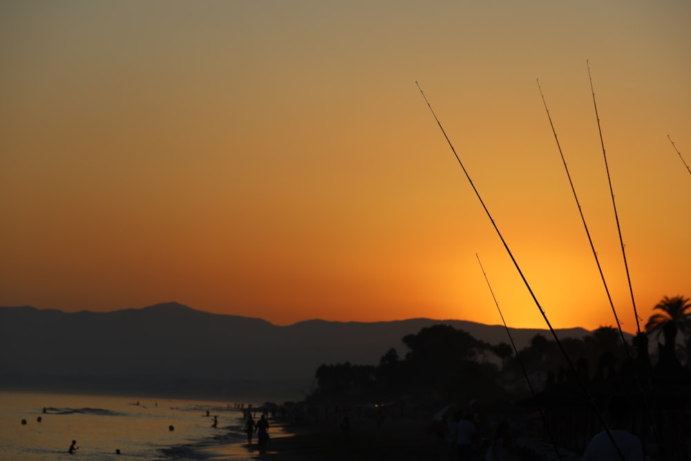 the sun is setting over a beach with people in the water