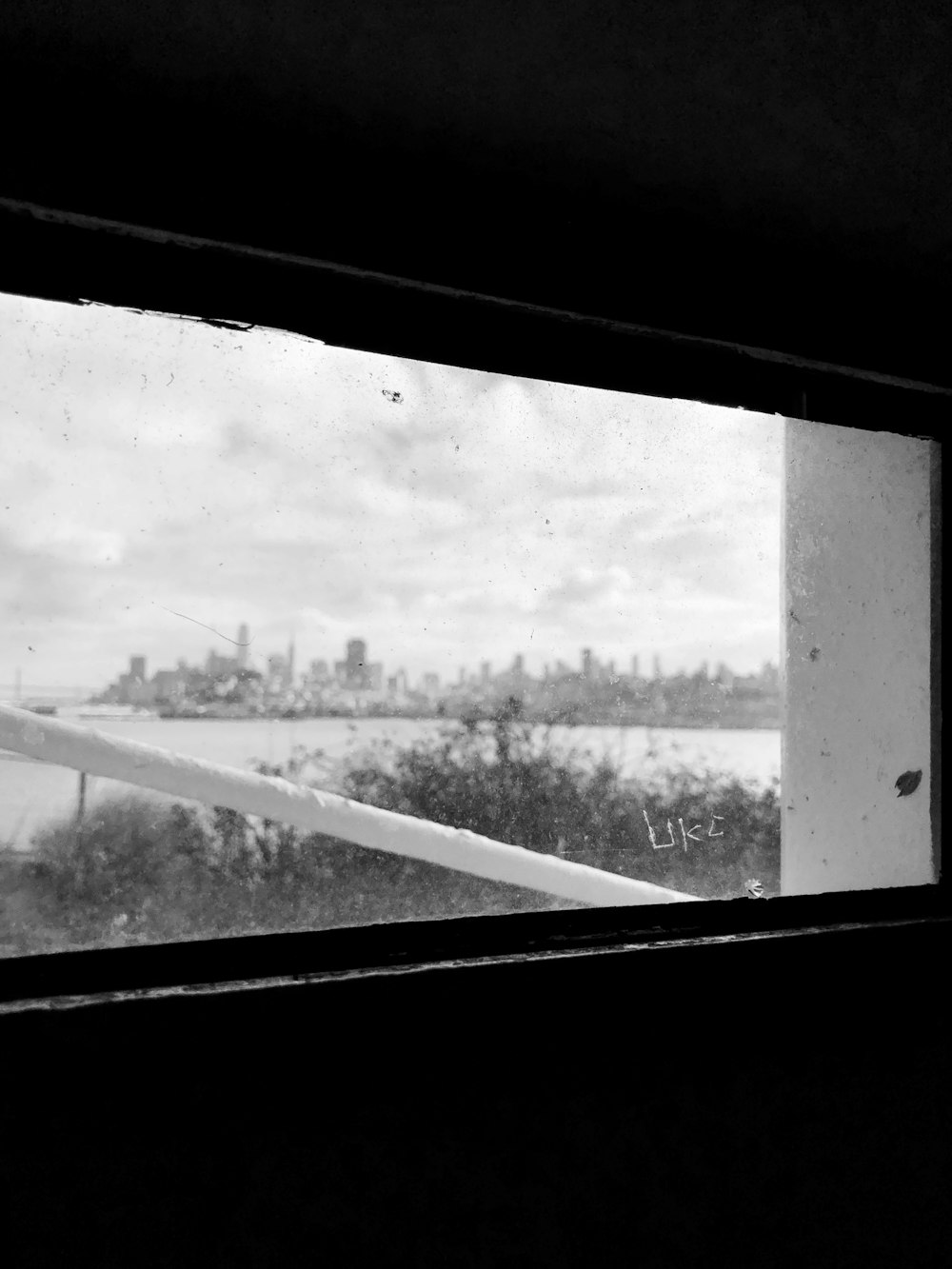 a black and white photo of a window with a view of a city