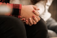 Close-up of hands joined in solidarity, painted with peachy pink nail polish.