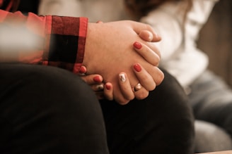 Close-up of hands joined in solidarity, painted with peachy pink nail polish.