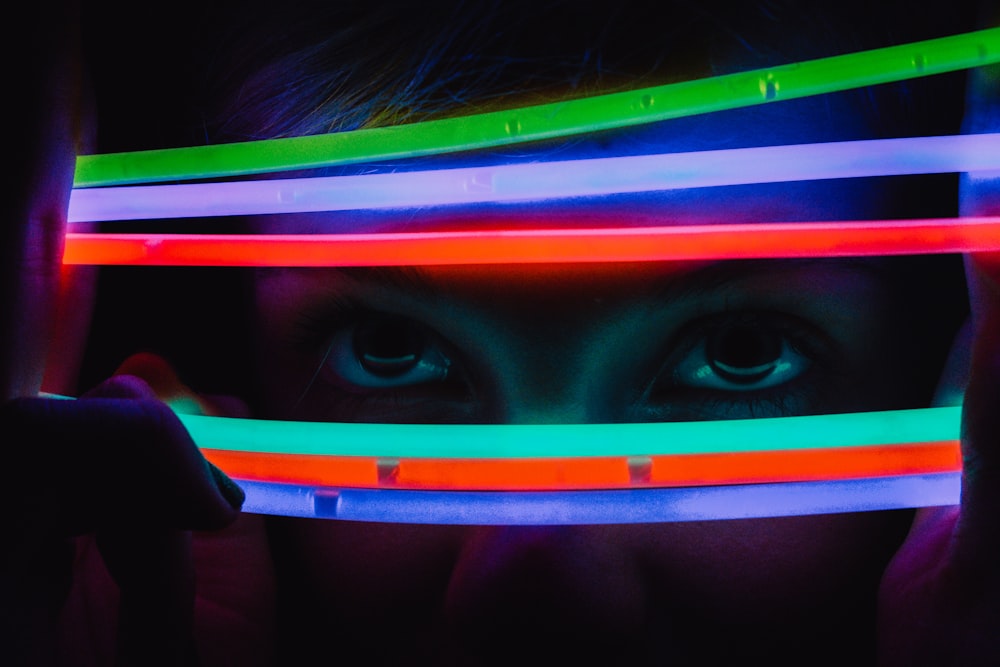 a person holding a neon light up in front of their face