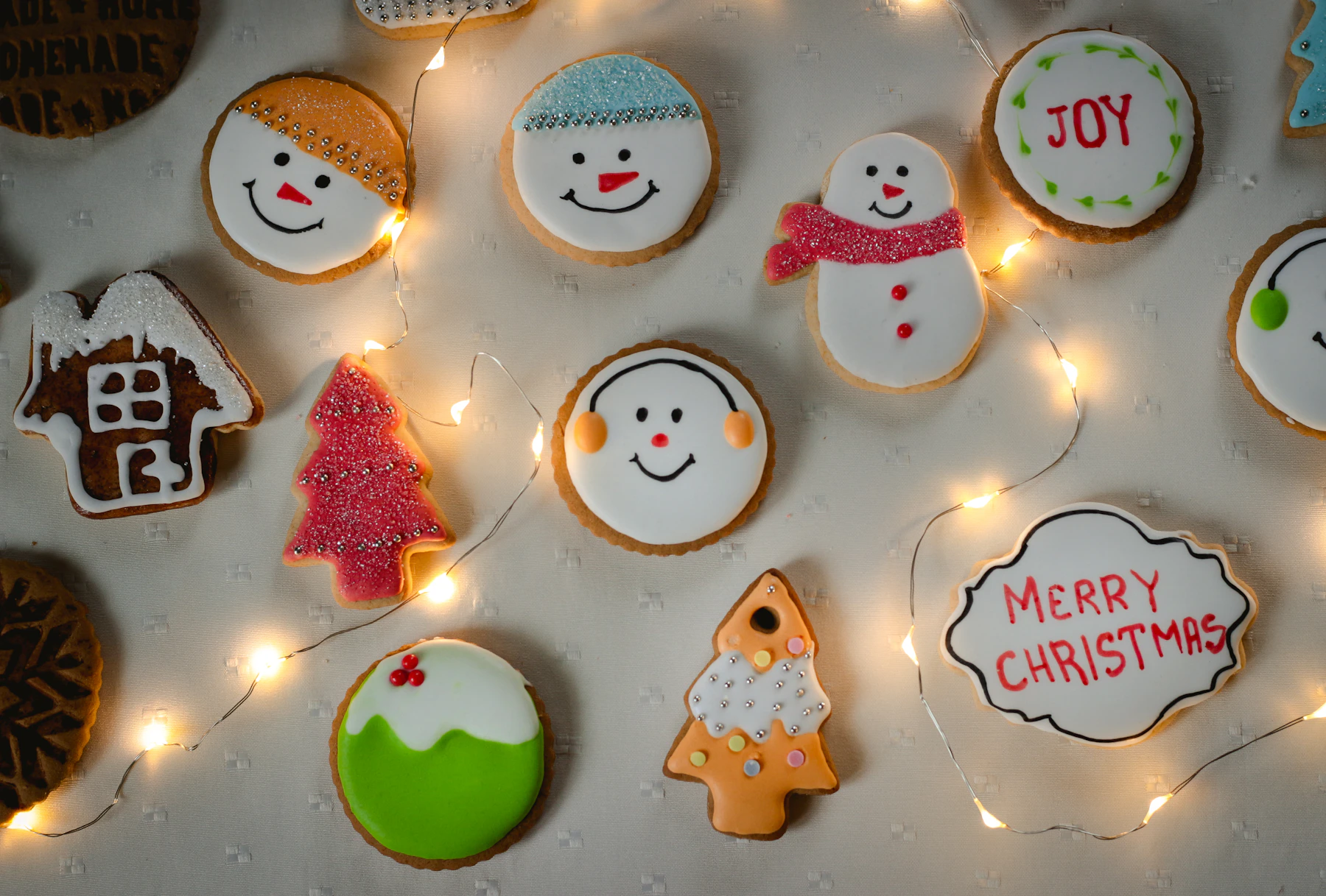 Round and shaped sugar cookies decorated with royal icing snowmen, trees and lettering