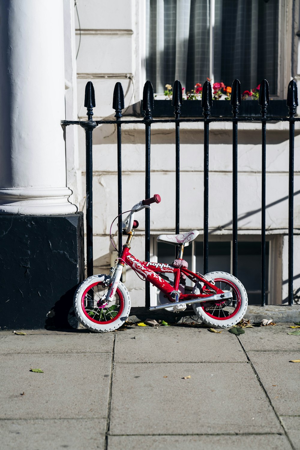 BMX bike parked beside fence and building during day