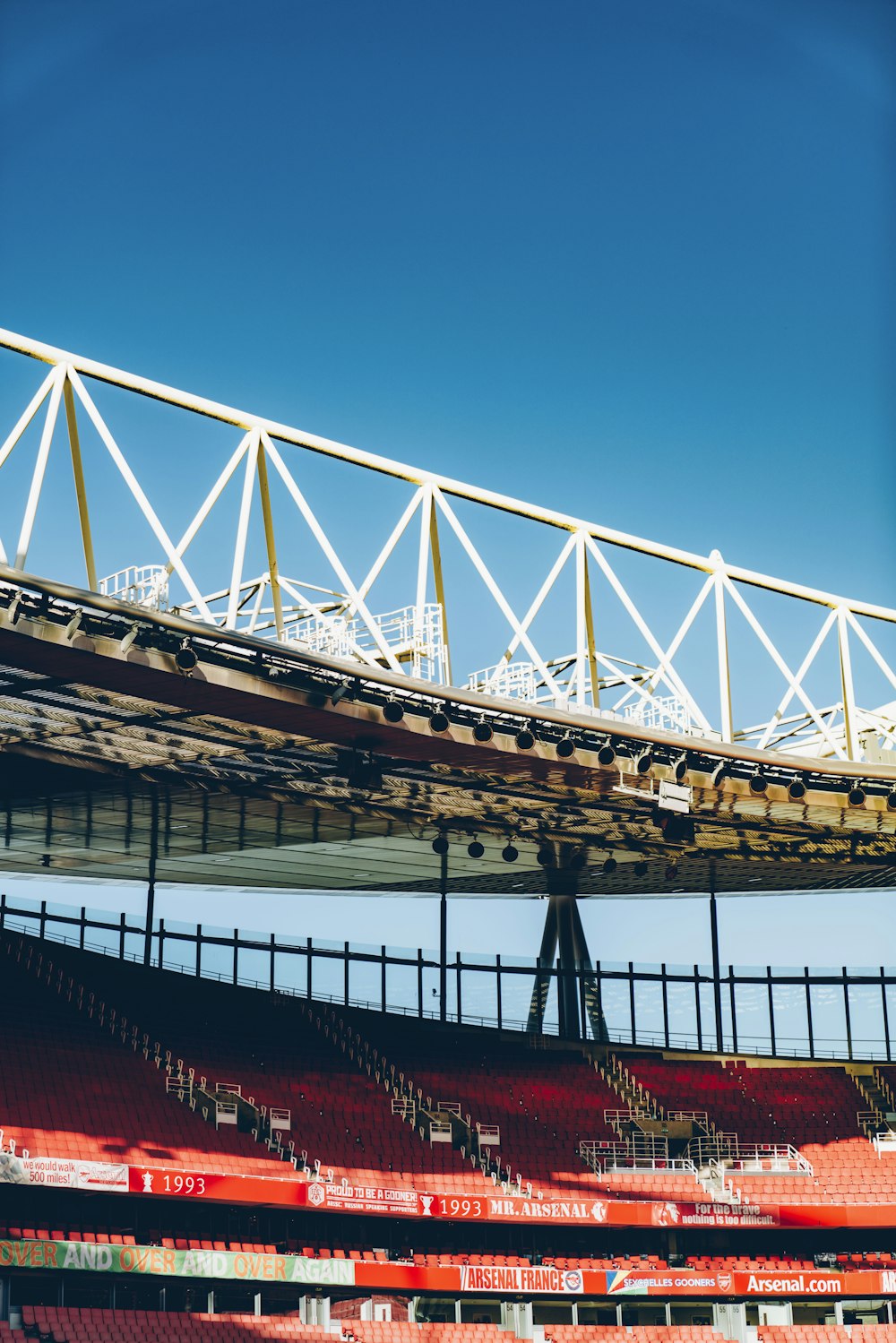 an empty stadium with red seats under a bridge
