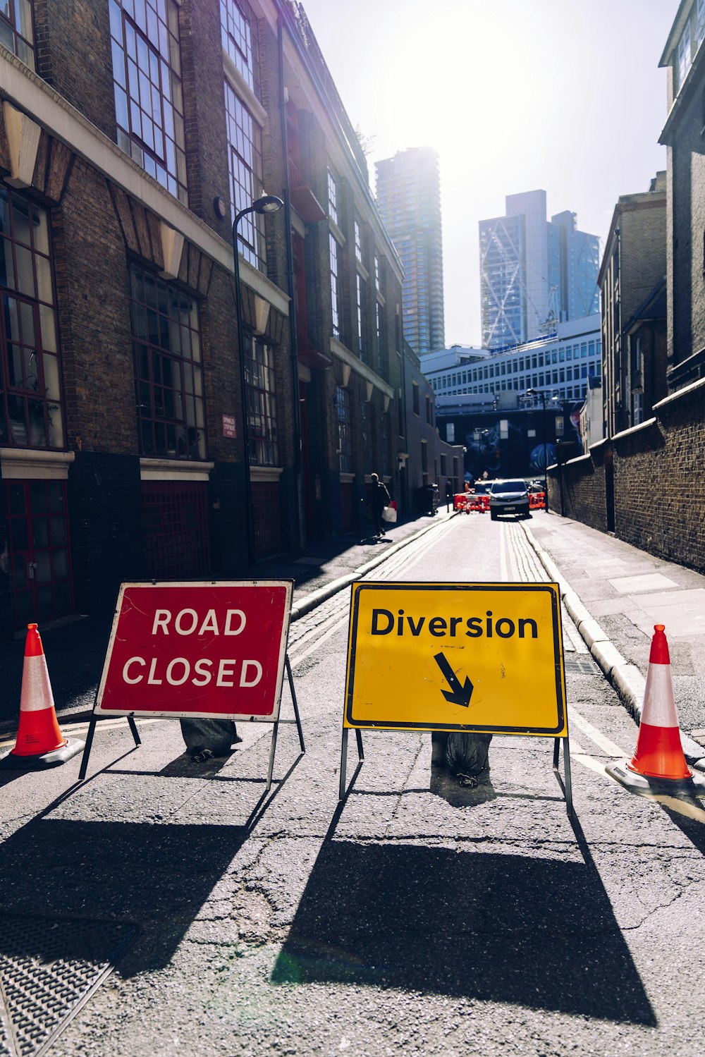 two traffic cones in between road closed and diversion road signs viewing buildings during daytime