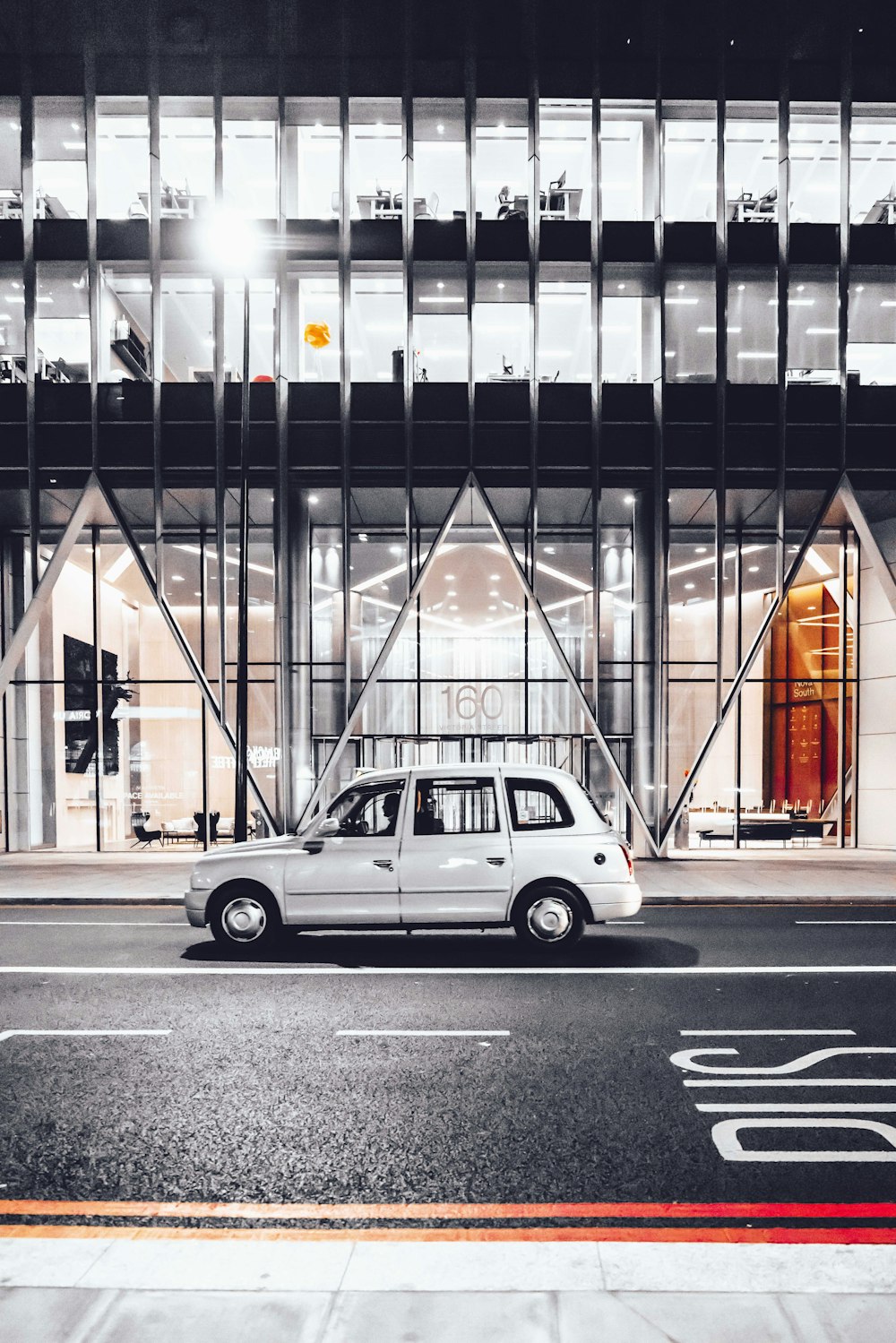 white 5-door hatchback on road near clear glass walled building