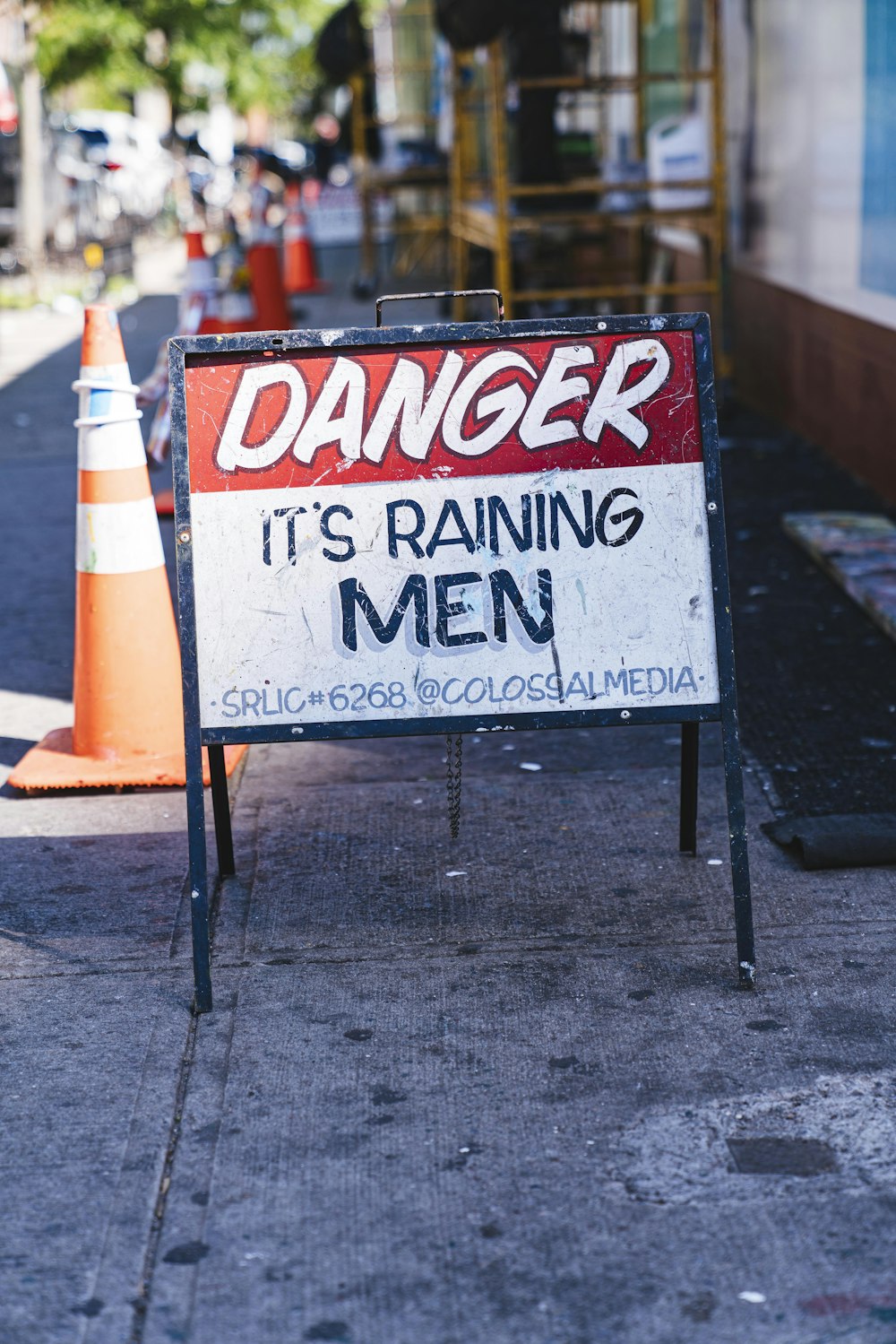 danger it's raining men signboard on sidewalk