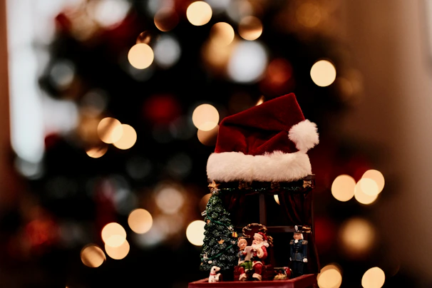 A cozy scene featuring classic red Christmas hats arranged on a rustic wooden table with soft fairy lights in the background.