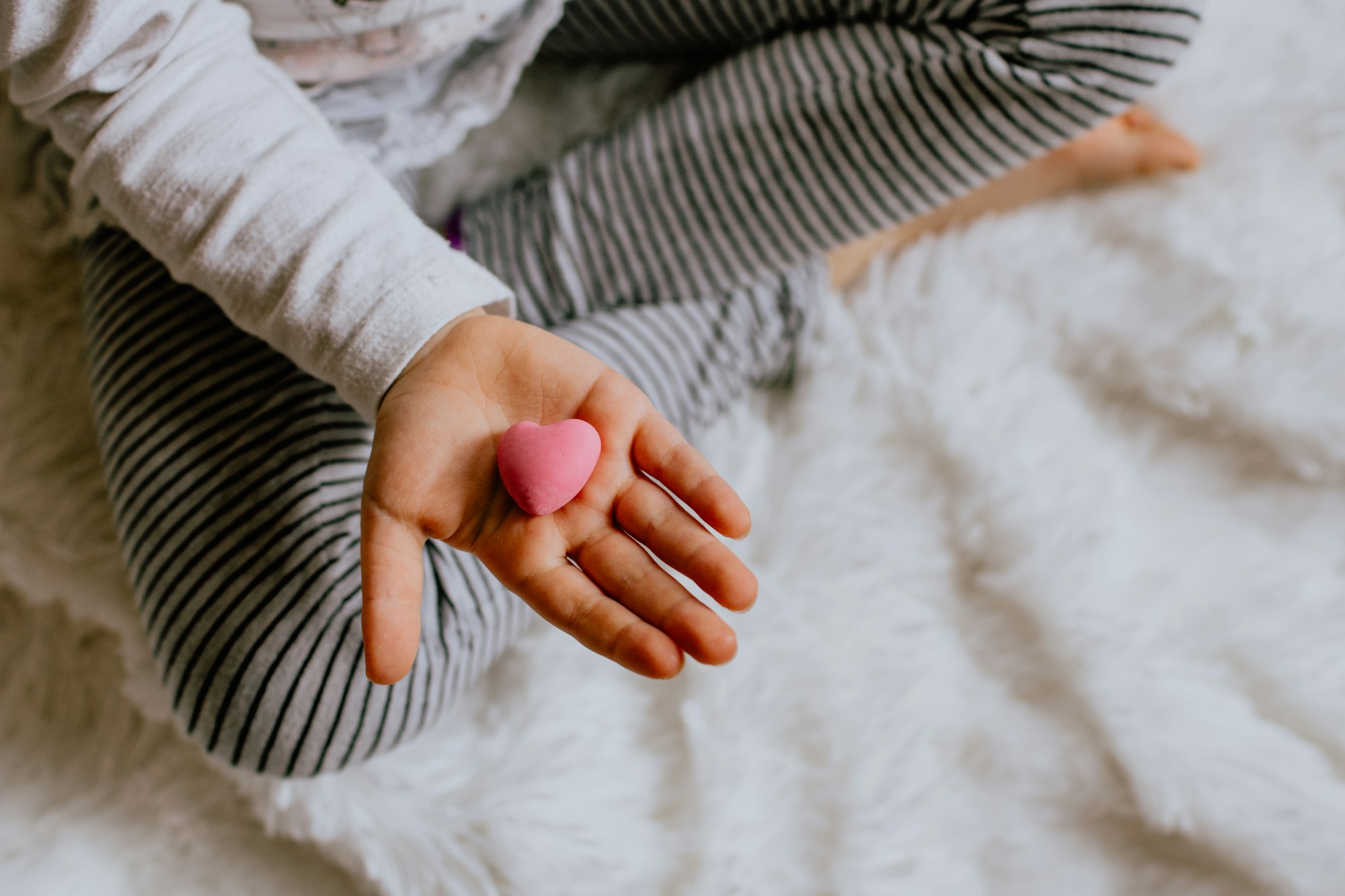 Child’s hand holding a pink heart toy 