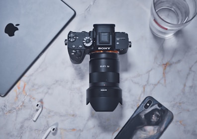 A flat lay of lifestyle gear including a Sony A7 IV camera, fitness bands, and espresso tools.