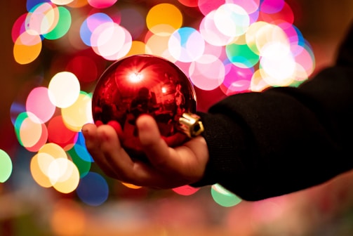 Close-up of a hand holding a bright, eco-friendly Christmas ornament glowing softly in warm light.