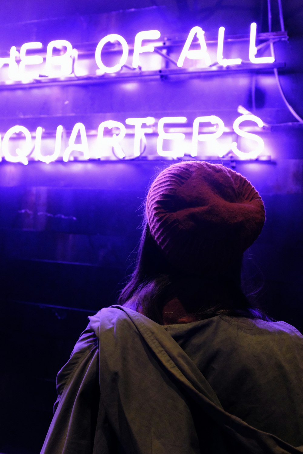 person wearing maroon knit cap in front of neon light signage