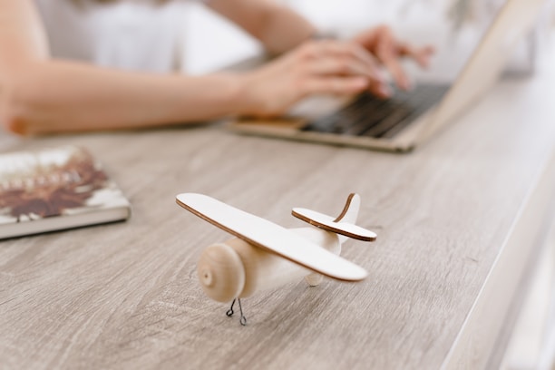 Close-up of hands typing on a keyboard with a world map and airplane model nearby.