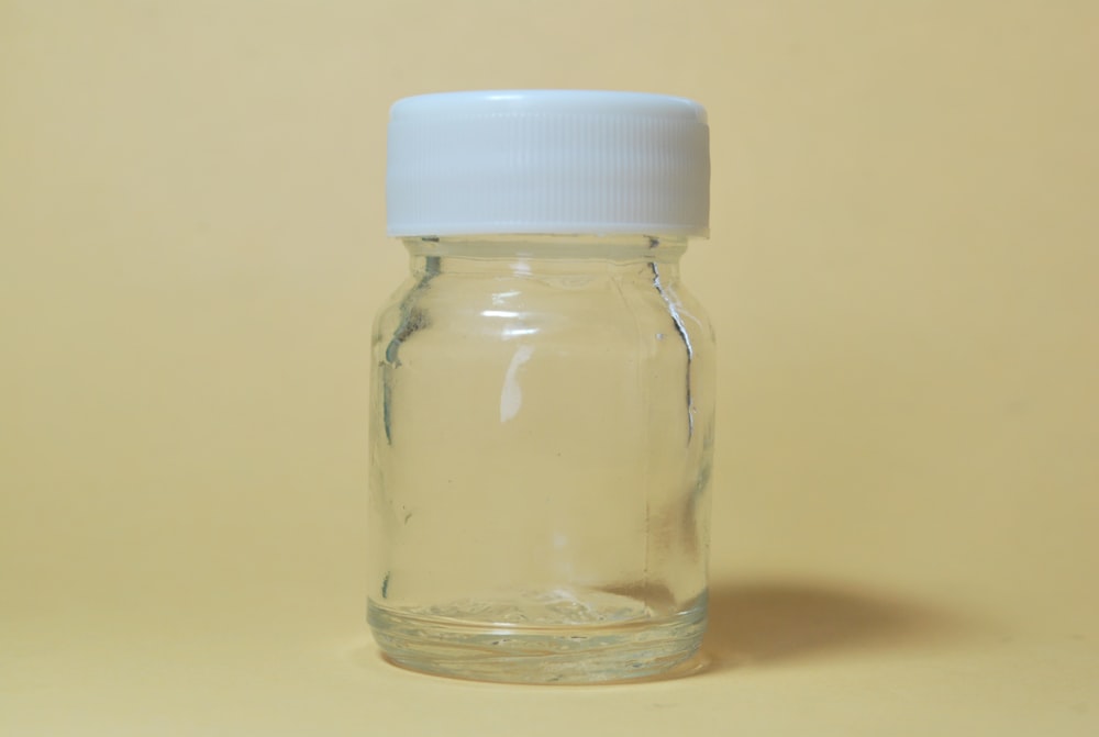 empty clear jar with white lid on yellow surface
