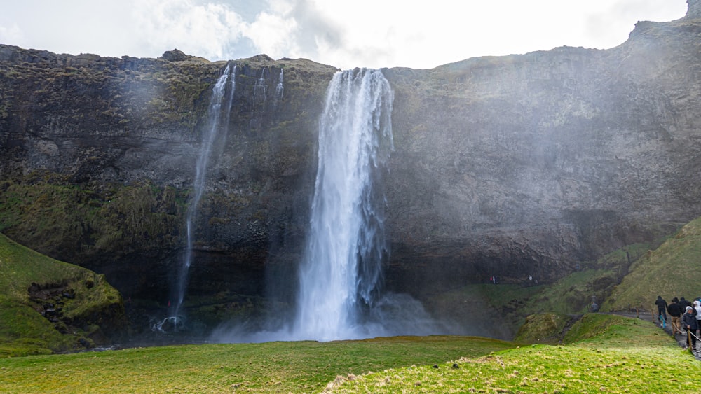 people on road near waterfalls during day