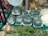 Plastic-wrapped broccoli is neatly stacked in trays, surrounded by various fresh vegetables including cauliflower and a type of root vegetable with leafy green stalks. The background features a poster with the text 'Iyi Tarim Uygulamalari' and an image of fruits.