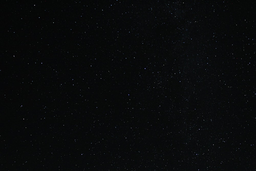 a night sky with stars and a plane in the foreground