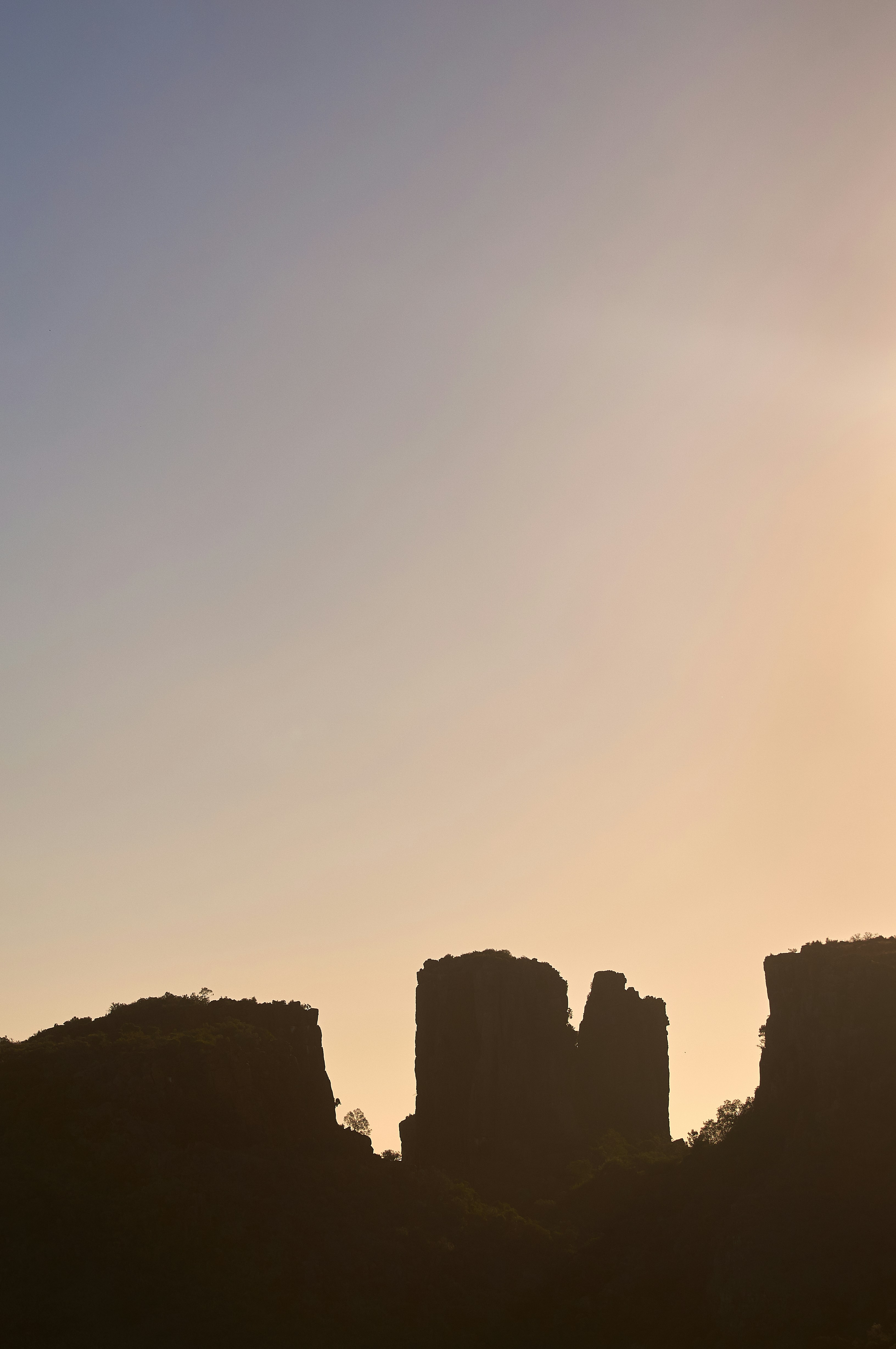 the sun is setting behind a rocky outcropping