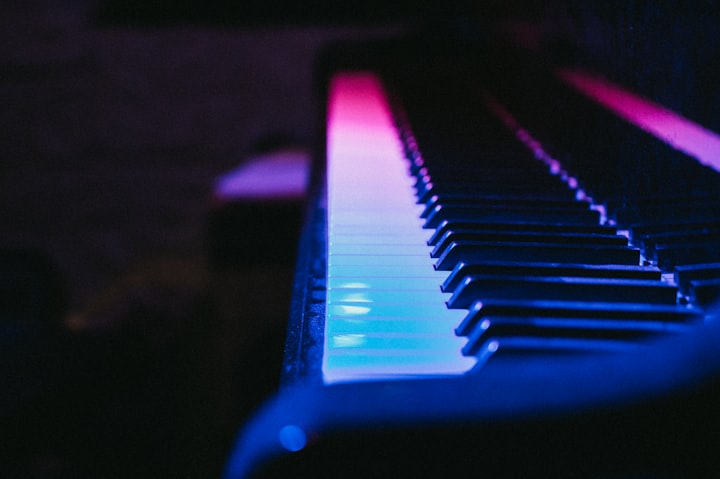 Piano keys coloured by blue and pink light.