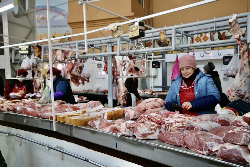 photography of women standing in front of meats