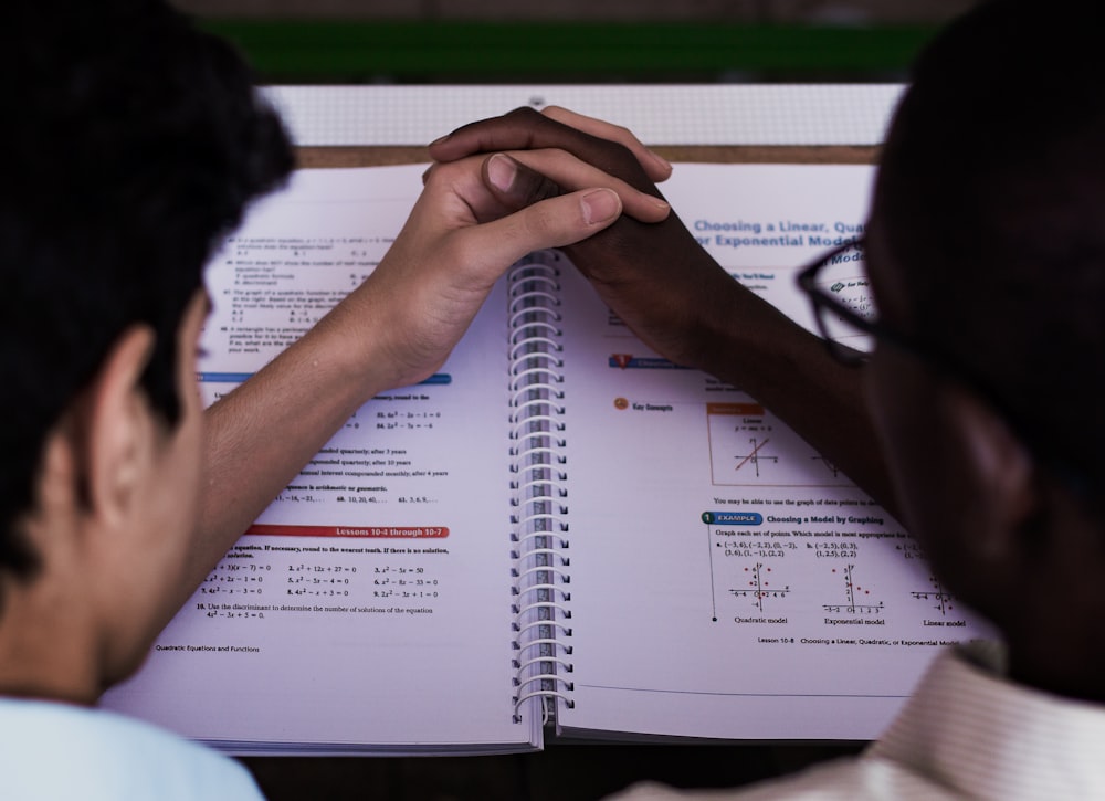 two persons holding hands on book