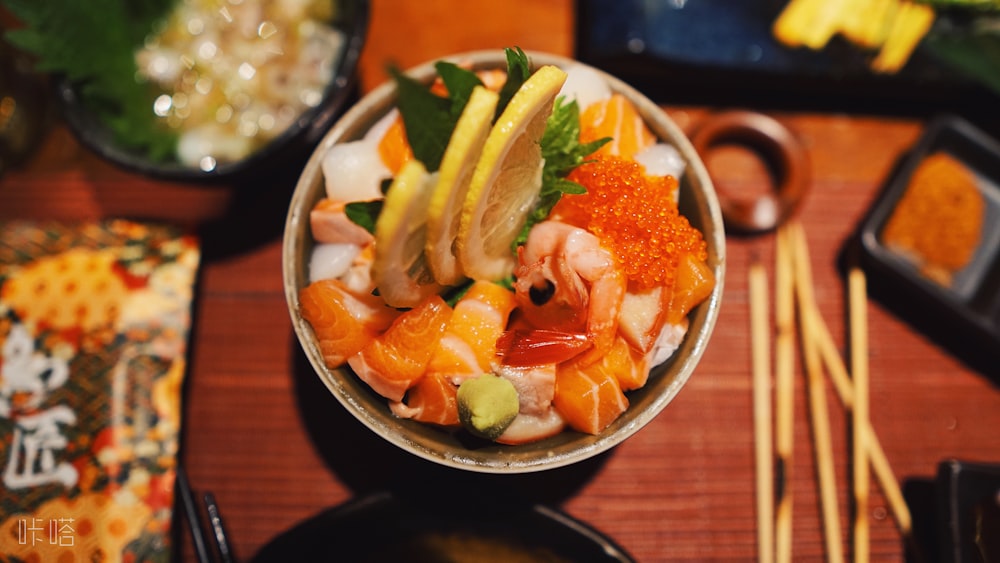 sushi with fruits in white bowl on top of table