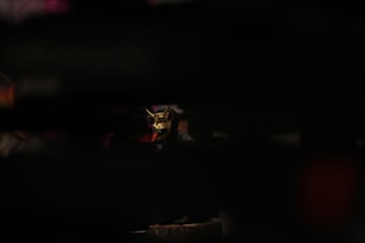 A mysterious black mask with red accents illuminated by soft, focused lighting.