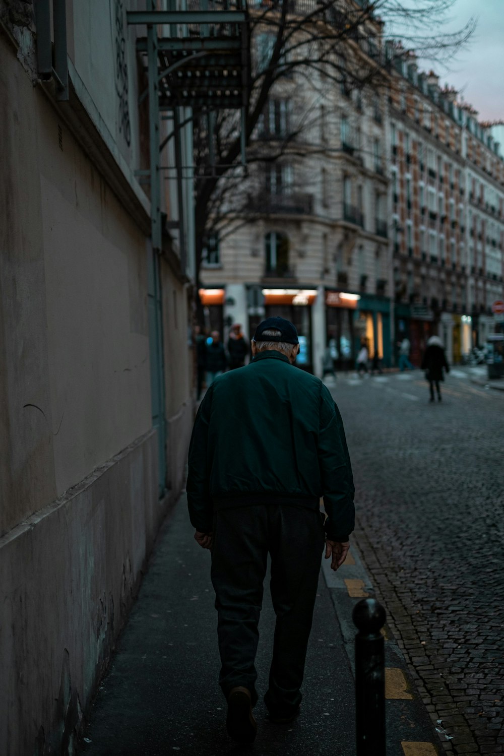 man walking on road side beside wall