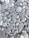 A collection of smooth, rounded gray stones of various sizes and shapes. The stones are tightly packed together, displaying slight variations in color and texture, with some visible white veins and lines.