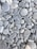 A collection of smooth, rounded gray stones of various sizes and shapes. The stones are tightly packed together, displaying slight variations in color and texture, with some visible white veins and lines.