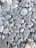 A collection of smooth, rounded gray stones of various sizes and shapes. The stones are tightly packed together, displaying slight variations in color and texture, with some visible white veins and lines.