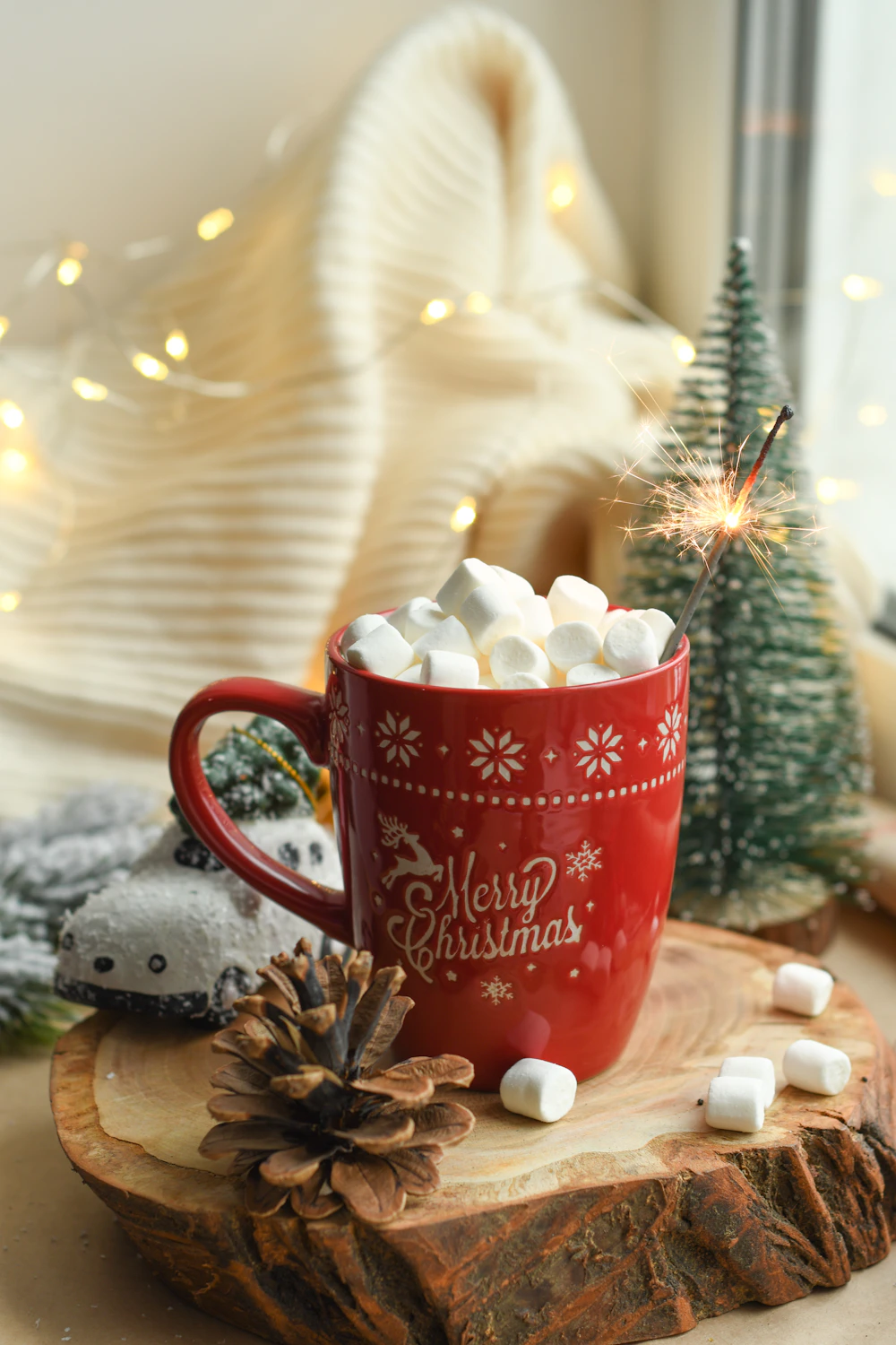 Marshmallows in rode mok naast bruine dennenappel op bruine snijplank