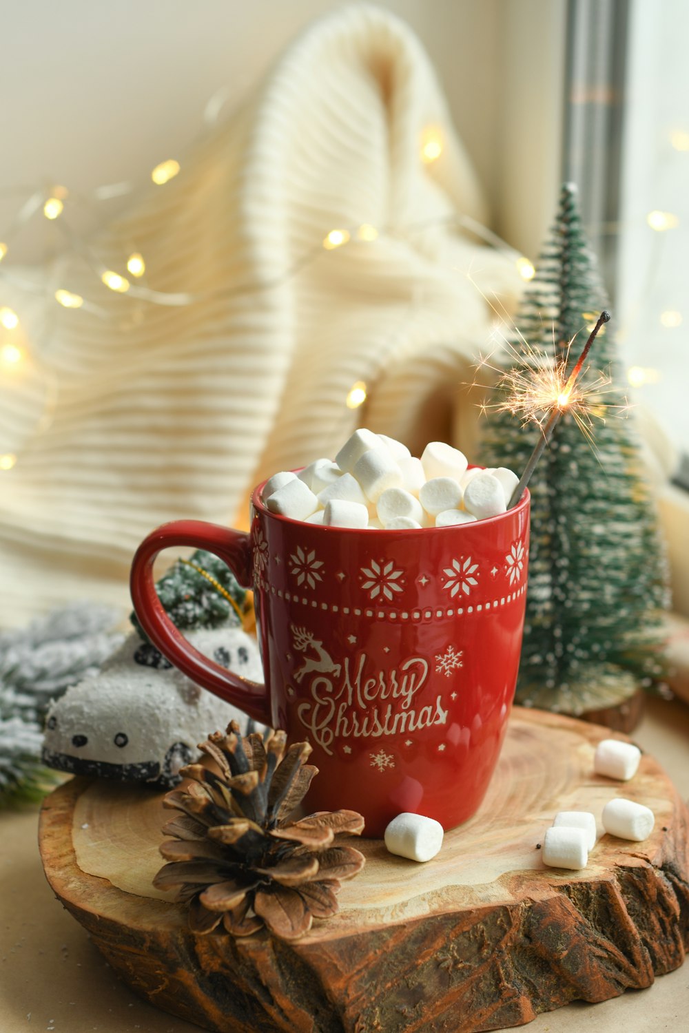 marshmallows in red mug beside brown pine cone on brown chopping board