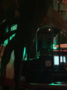 A vintage computer with a glowing green screen sits on a wooden desk, bathed in warm ambient light.