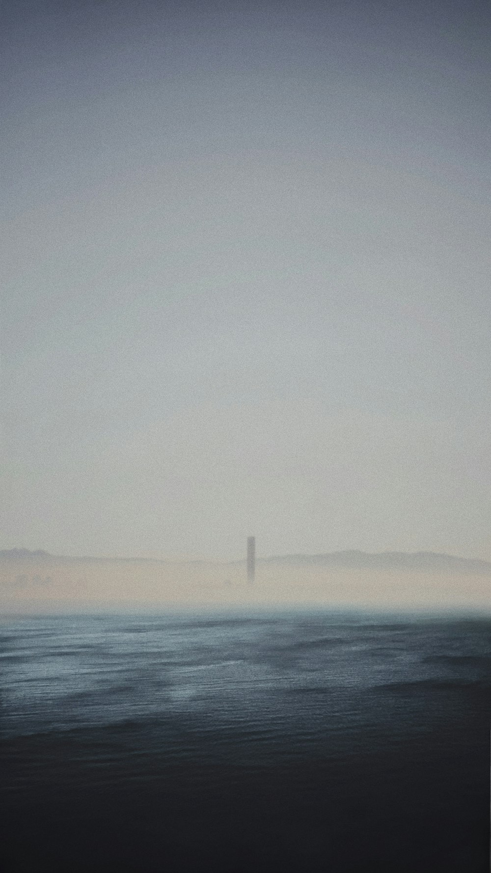 a large body of water with a lighthouse in the distance