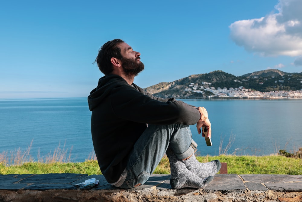 Homme assis sur un banc en béton surplombant la plage