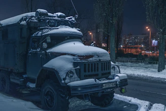 Tow truck pulling a car on a snowy Fort McMurray street at dusk.