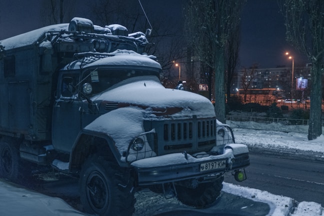 Tow truck assisting a stranded car on a quiet city street at dusk.