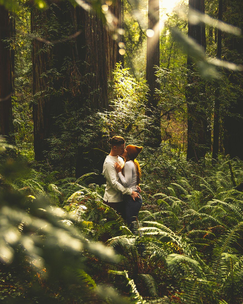 couple wearing white kissing each other in forest during sunrise