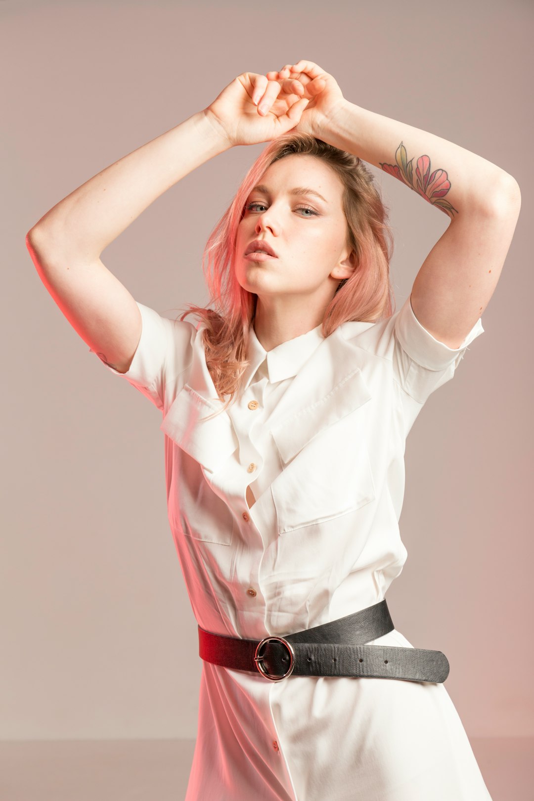 woman wearing white collared button-up dress standing while putting both hands on her head