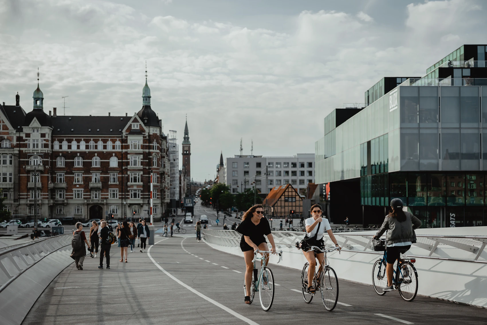 Cyclists crossing a wide modern bridge in central Copenhagen