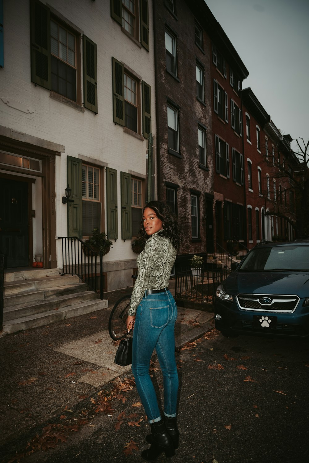 woman wearing gray long-sleeved shirt and blue denim high-waist jeans near car