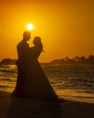 newly wed couple facing each other while standing near seashore viewing full moon
