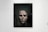 A framed artwork features a large, textured face that appears to be eroded or damaged. The piece is displayed in a gallery setting with people observing it. The gallery is well-lit, and the artwork contrasts against the plain white wall.